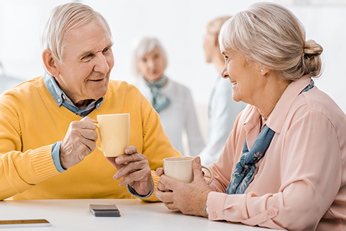 Elderly couple sitting at a white table having a cup of coffee